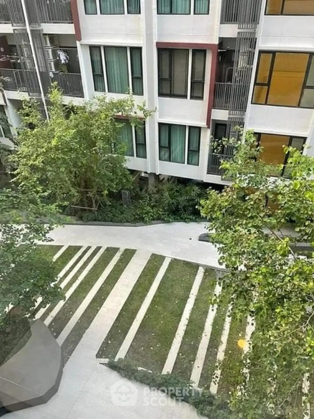 Modern apartment building with lush green garden view from above.