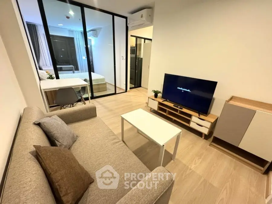 Modern living room with cozy sofa and TV, open layout to bedroom, stylish decor.