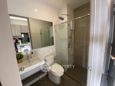 Modern bathroom with glass shower and sleek fixtures in contemporary apartment.