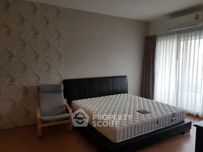Spacious bedroom with modern decor and large window for natural light.