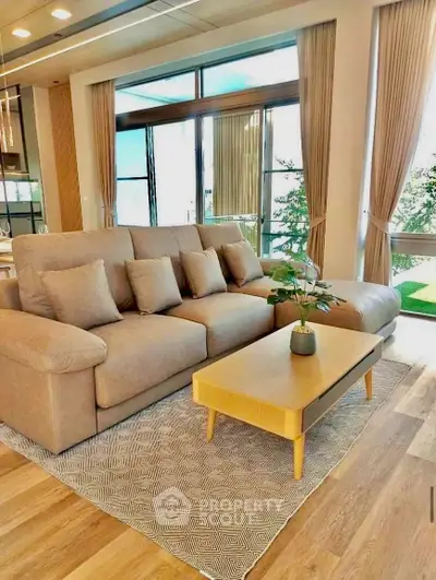 Spacious living room with modern sofa and large windows offering natural light and scenic views.