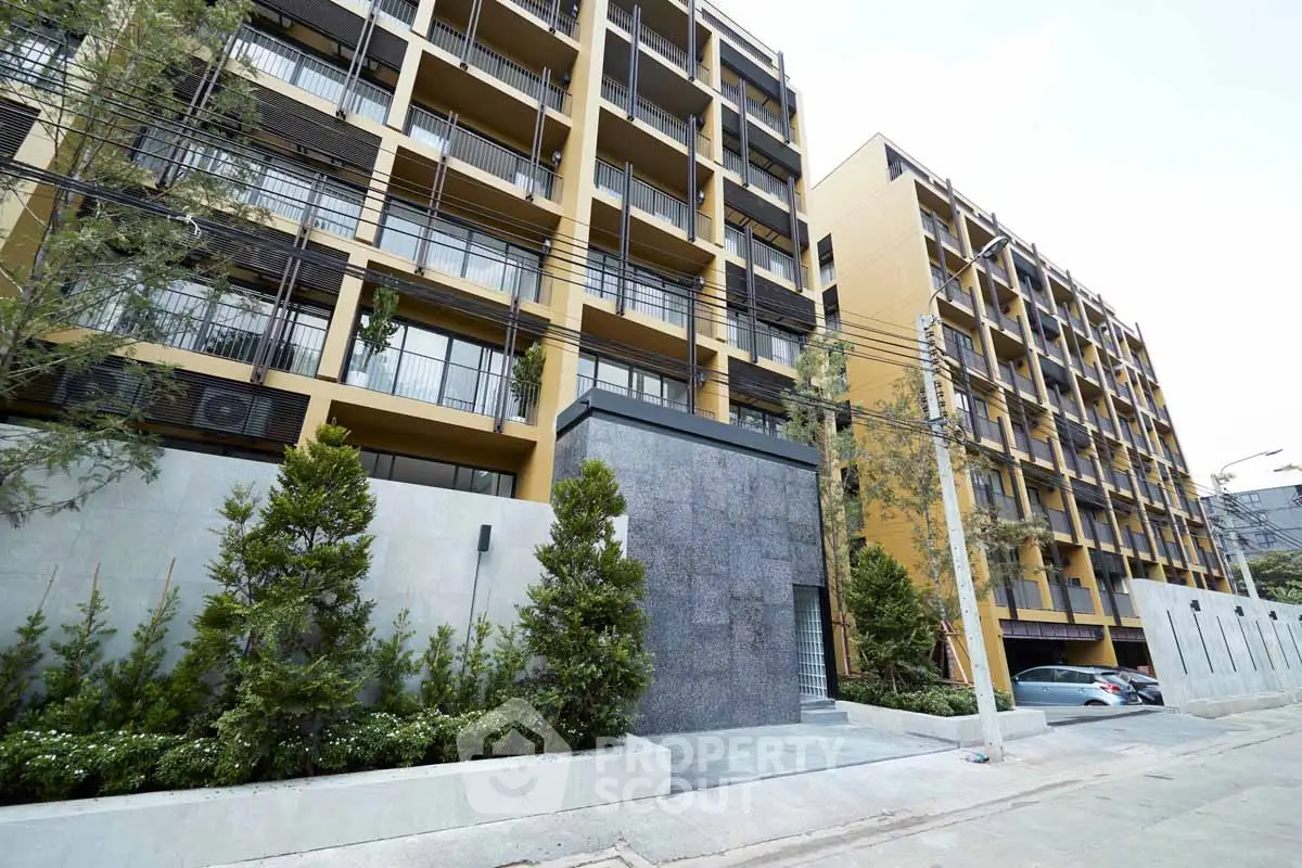 Modern apartment building exterior with lush greenery and sleek design.