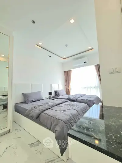 Modern bedroom with sleek design and natural light, featuring a stylish bed and marble accents.