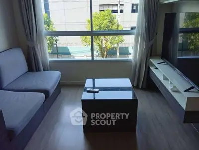 Modern living room with large window and sleek furniture, perfect for relaxation and entertainment.