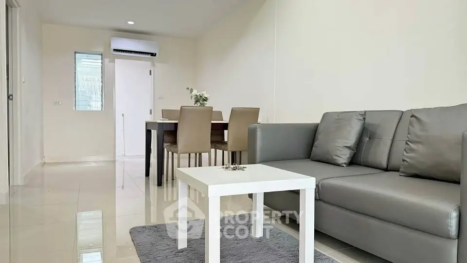 Modern living room with sleek furniture and dining area in open layout apartment.