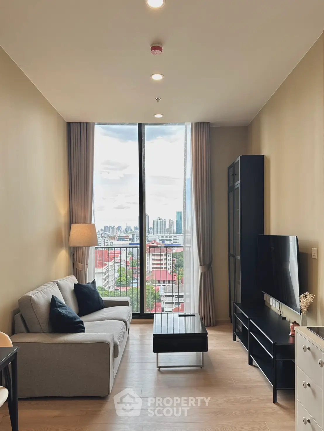 Modern living room with city view, stylish furniture, and floor-to-ceiling windows.