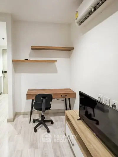 Modern study room with wooden desk, shelves, and TV in a compact space.