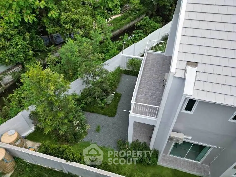 Modern house with spacious garden and balcony, surrounded by lush greenery, offering serene outdoor living.