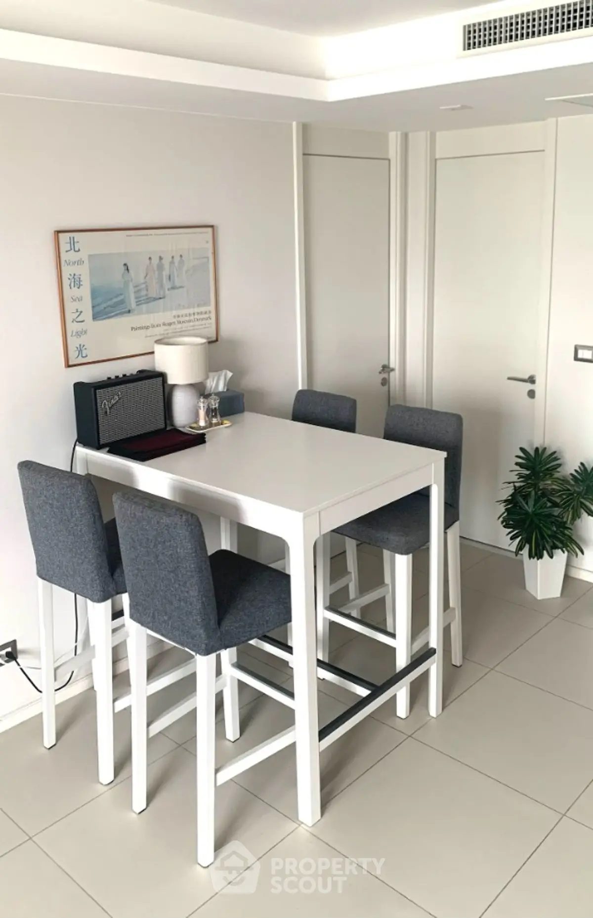 Modern dining area with sleek white table and stylish gray chairs in a contemporary apartment.