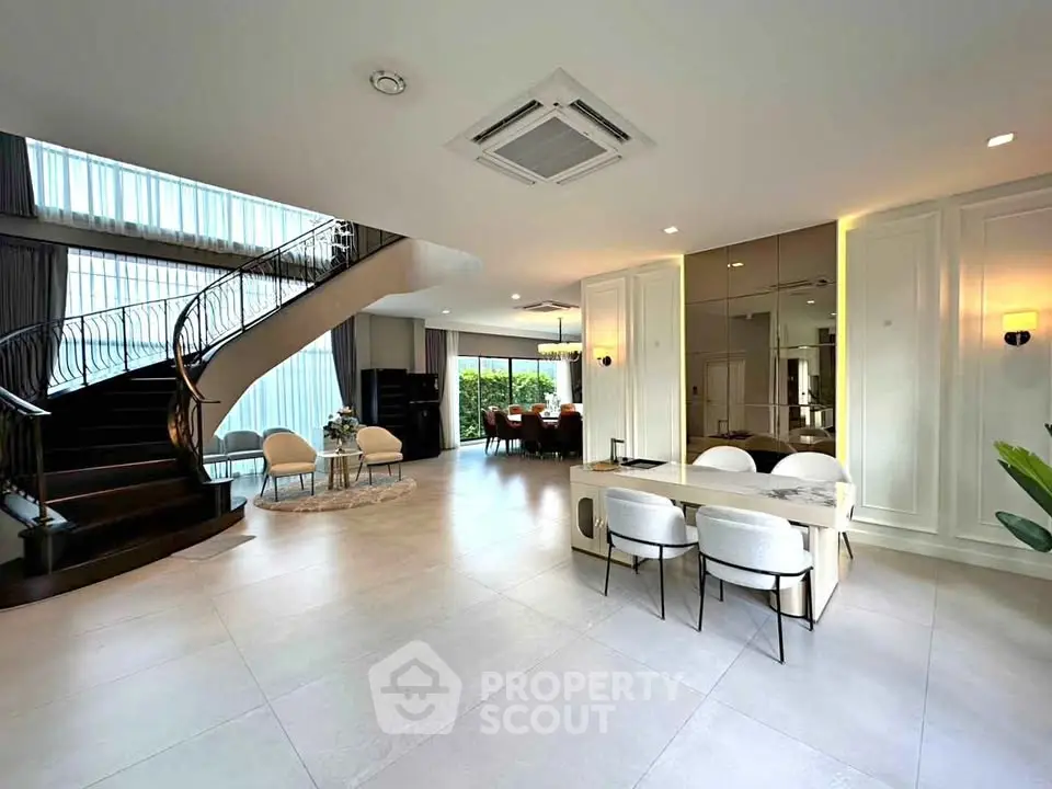 Luxurious open-plan living room with elegant staircase and dining area, perfect for modern living.