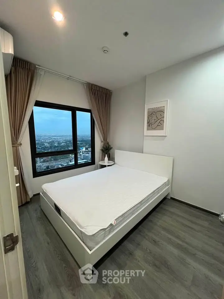 Modern bedroom with large window offering stunning city view, featuring minimalist decor and cozy ambiance.