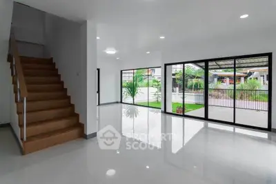 Spacious modern living room with large windows and staircase, offering abundant natural light.