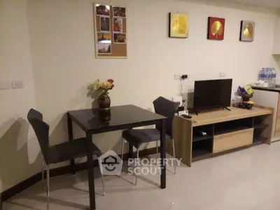 Modern living room with sleek furniture and wall art, featuring a compact dining area and entertainment setup.