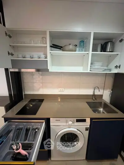 Modern compact kitchen with washing machine and open cabinets showcasing sleek design.
