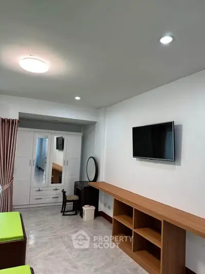 Spacious bedroom with modern furnishings and wall-mounted TV, ideal for comfortable living.