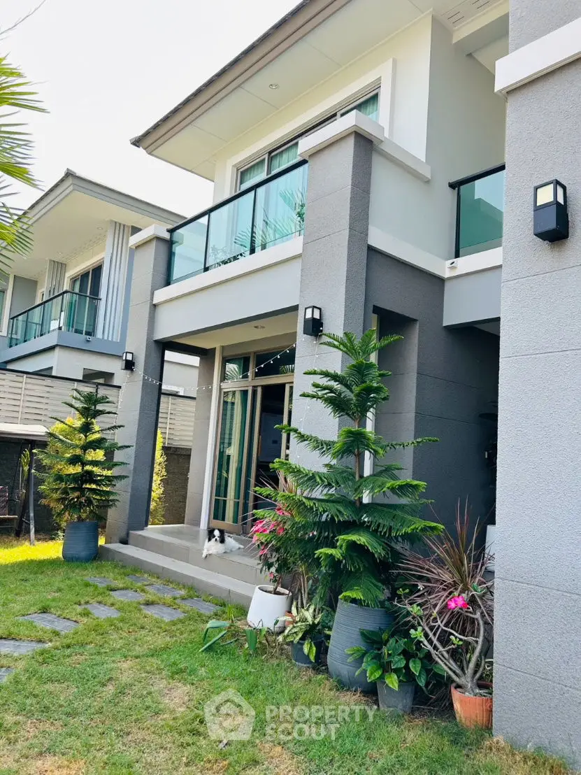 Modern two-story house with lush garden and glass balcony, perfect for family living.