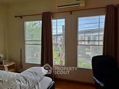 Cozy bedroom with large windows offering a serene view of the neighborhood, perfect for relaxation.