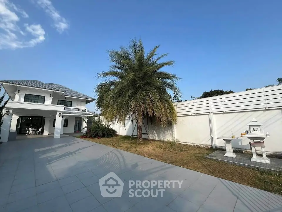 Spacious modern home with lush garden and palm tree, perfect for family living.