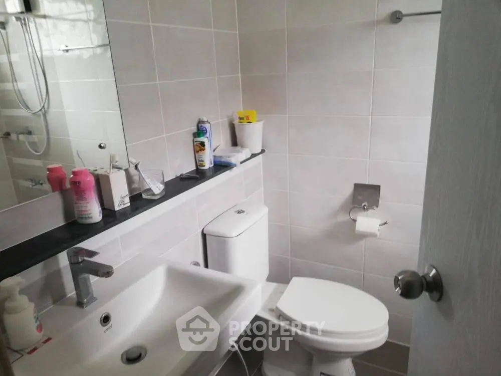 Modern bathroom with sleek fixtures and tiled walls, featuring a compact design.
