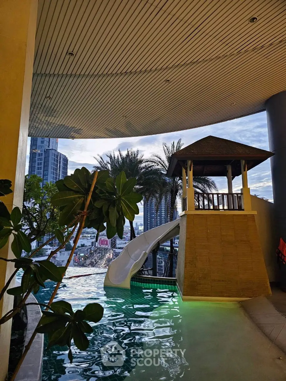 Luxurious rooftop pool with slide and city view, perfect for urban relaxation.