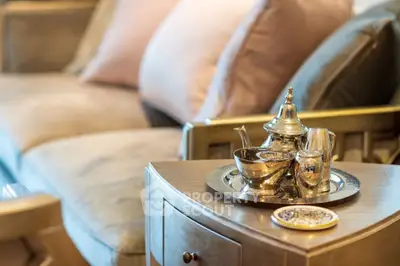 Elegant living room with luxurious sofa and ornate tea set on wooden table, exuding comfort and style.