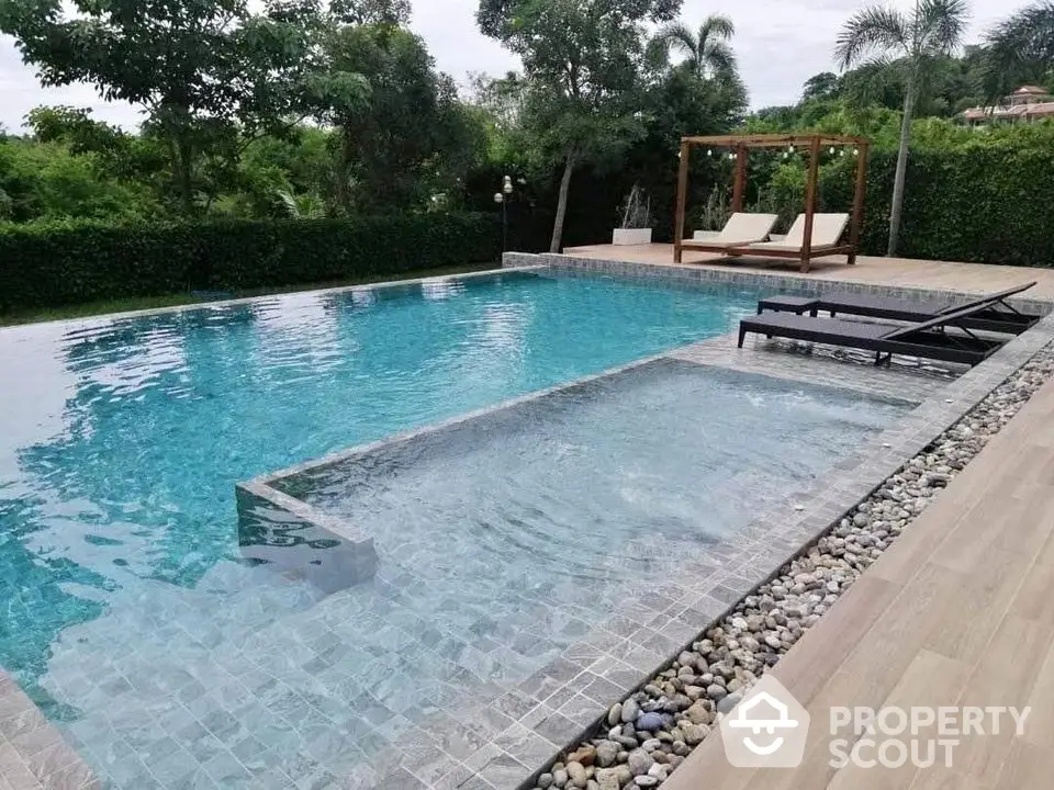 Luxurious outdoor pool with sun loungers and lush greenery, perfect for relaxation and leisure.