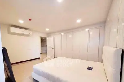 Spacious modern bedroom with sleek white wardrobe and comfortable bed in a well-lit interior.
