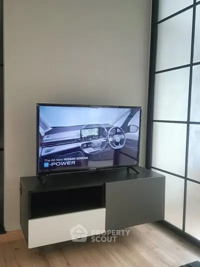 Modern living room with sleek TV stand and flat-screen TV on wooden floor.