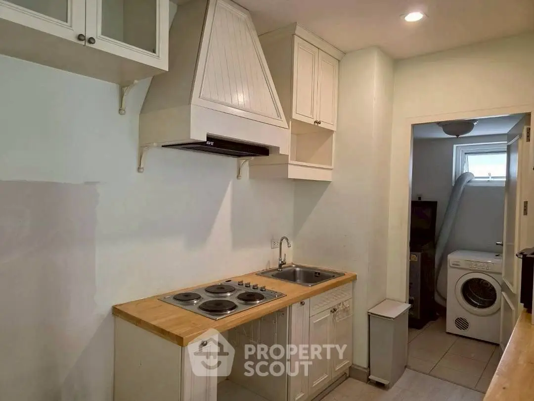 Charming compact kitchen with wooden countertops and adjacent laundry area