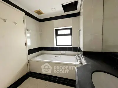 Spacious bathroom with bathtub and modern fixtures in elegant black and white design.