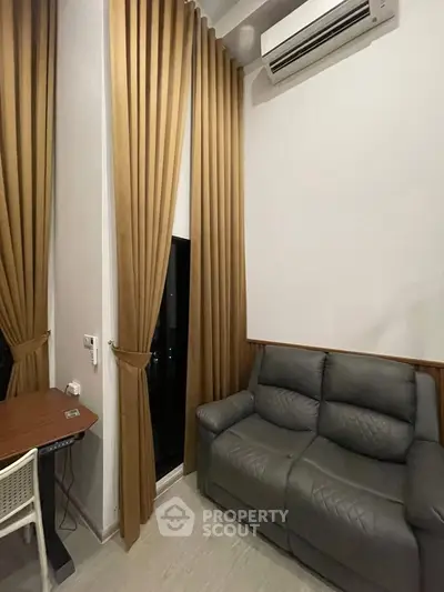 Cozy living room with modern sofa, desk, and air conditioning, featuring elegant floor-to-ceiling curtains.