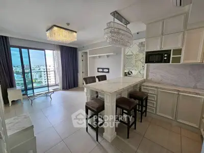 Luxurious open-plan kitchen and living area with elegant chandeliers and city view.