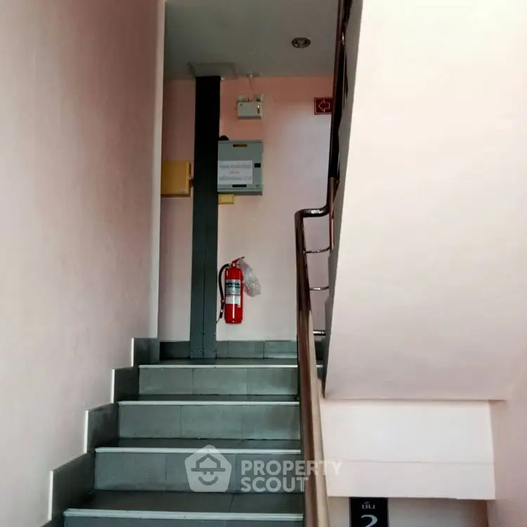 Staircase in a residential building with fire safety equipment and modern design.