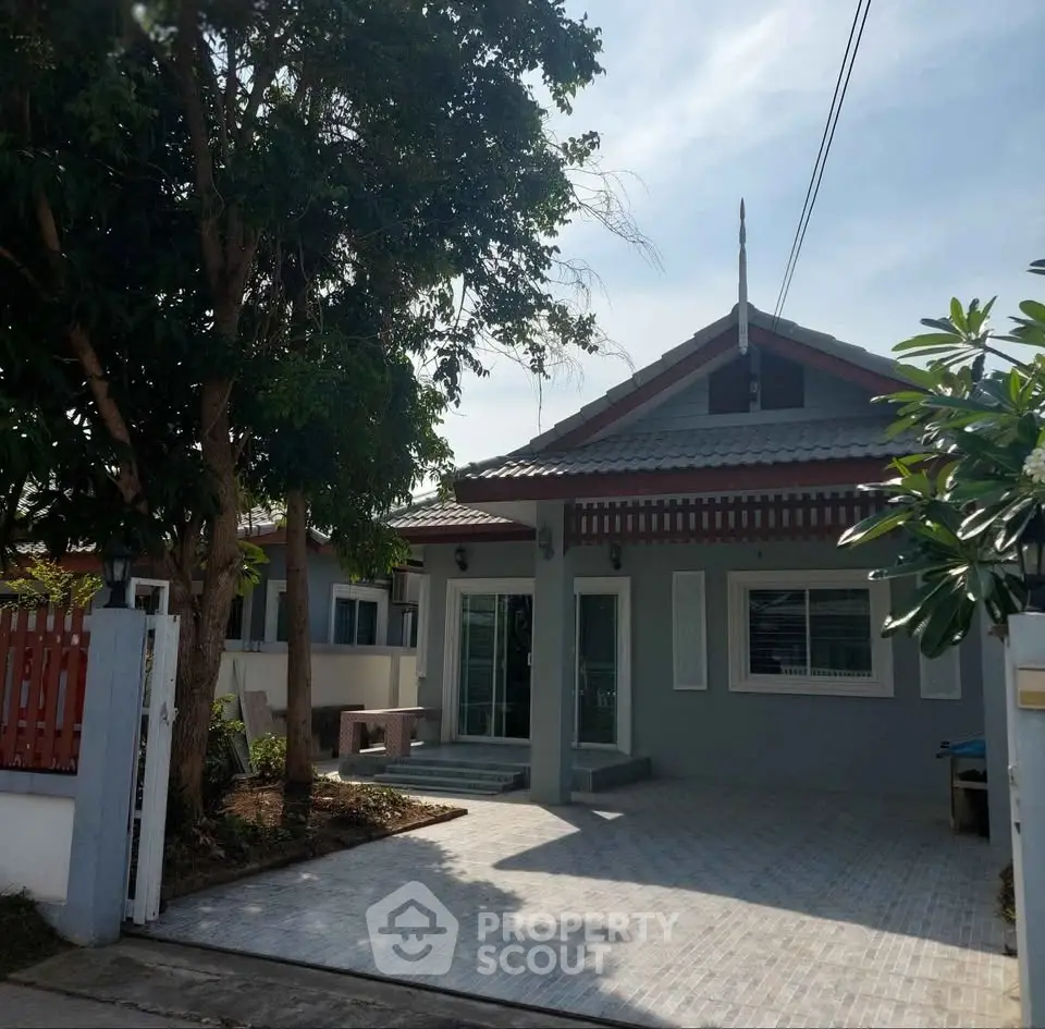 Charming single-story house with spacious driveway and lush greenery, perfect for serene living.