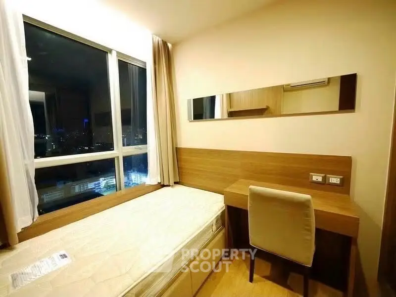 Cozy bedroom with city view, featuring a bed and study desk by the window.