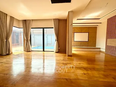 Spacious living room with wooden floors and pool view, perfect for modern living.