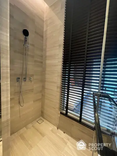 Modern bathroom with elegant wall tiles and sleek shower fixtures, complemented by stylish blinds and natural light.