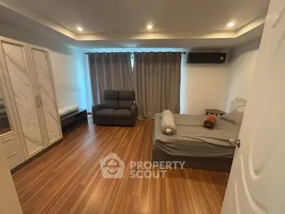 Spacious bedroom with modern decor and wooden flooring, featuring a cozy bed and ample storage.