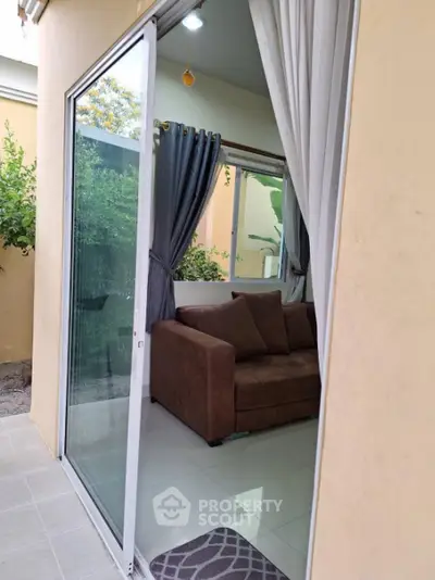 Charming small living room with sliding glass door and cozy brown sofa, perfect for relaxation.