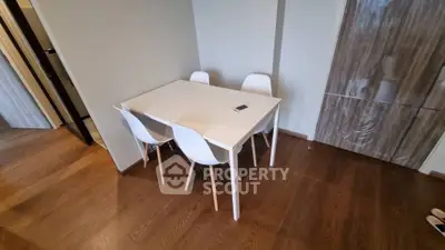 Modern dining area with sleek white table and chairs on polished wooden floor.