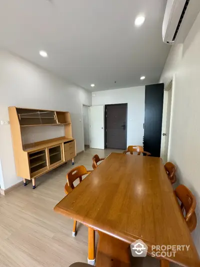 Spacious dining area with wooden furniture and modern lighting in a contemporary apartment.