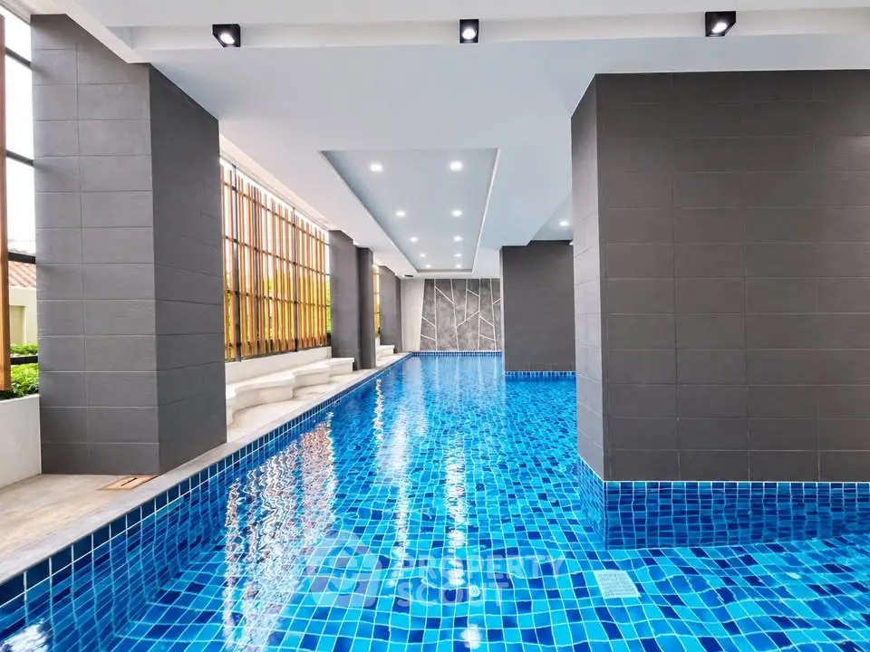 Luxurious indoor swimming pool with modern design and vibrant blue tiles in a high-end residential complex.