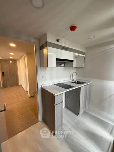 Modern compact kitchen with sleek cabinetry and integrated appliances in a stylish apartment.