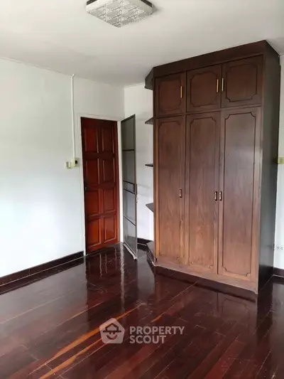 Spacious bedroom with wooden wardrobe and polished hardwood floors