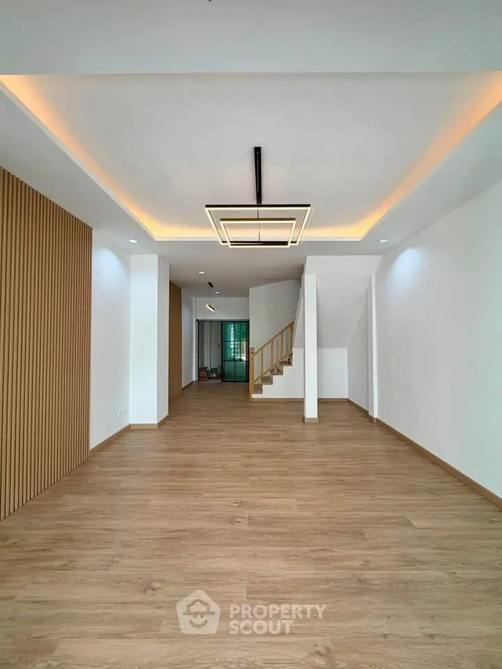 Spacious modern living room with elegant lighting and wooden flooring, perfect for family gatherings.