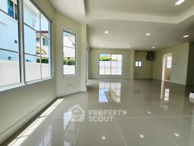 Spacious and sunlit living room with large windows and glossy tiled floors