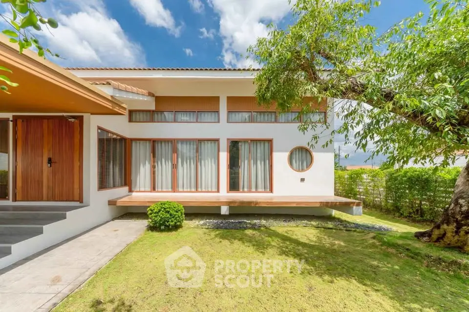 Stunning modern home exterior with lush garden and large windows, perfect for natural light lovers.