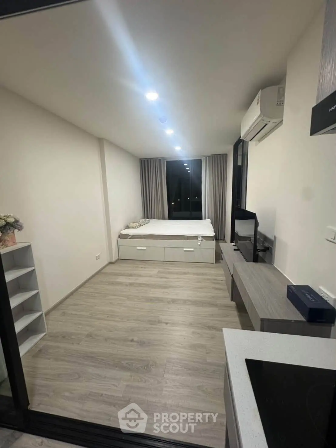 Modern studio apartment with sleek design and ample natural light, featuring a cozy bed and efficient layout.