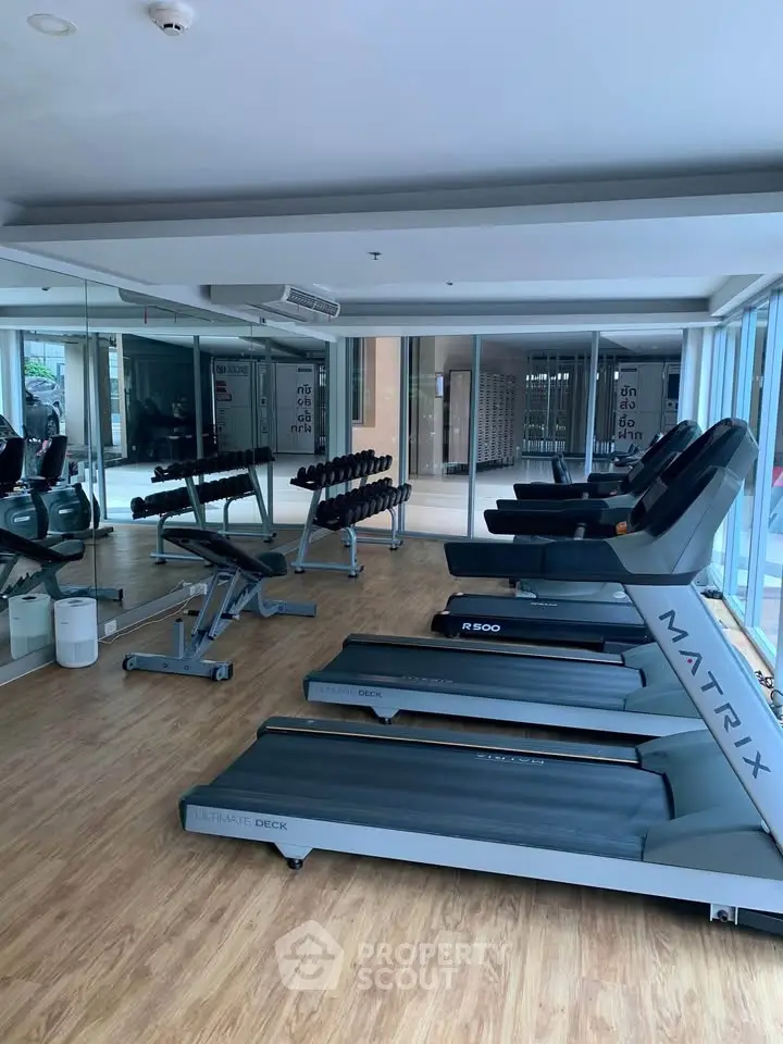 Modern gym with treadmills and weights in a sleek real estate property.
