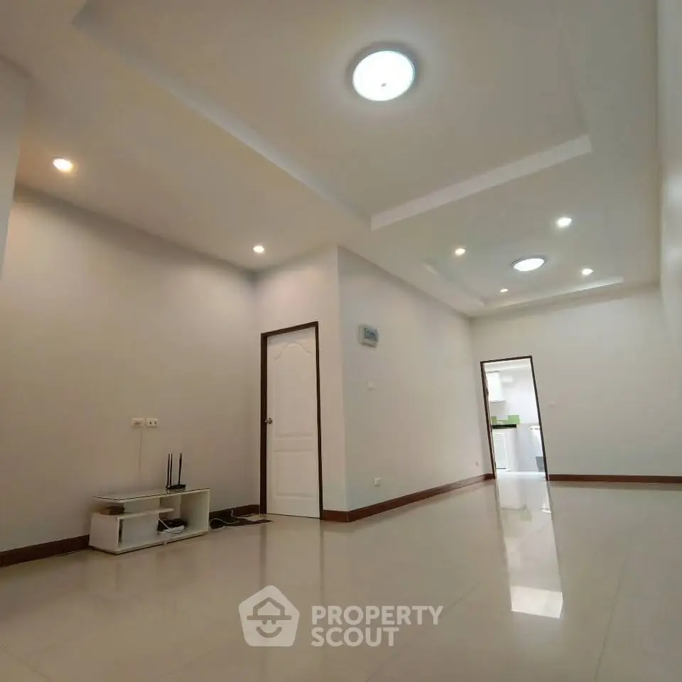 Spacious modern living room with recessed lighting and sleek tile flooring.